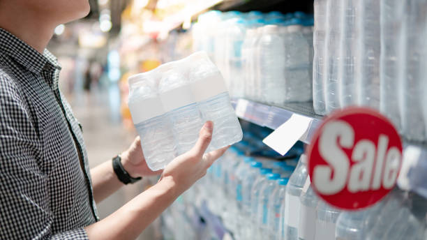 istock Shopper picking pack of water bottle from shelf 1153170147