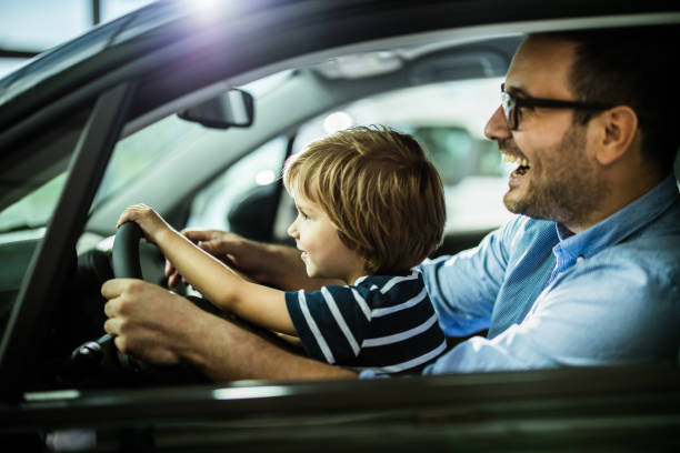 istock Happy father and son testing new car in a showroom. 1153170578