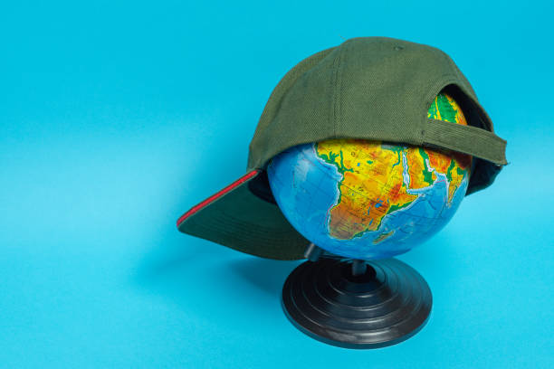 istock Globe with a green baseball cap on it on a blue background. Geographical names on the globe in Russian 1153171937