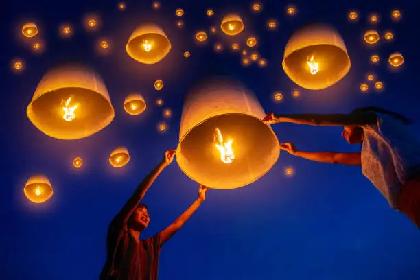 Thai's Family release sky lanterns to worship buddha's relics in yi peng festival, Chiangmai thailand. Thai people floating lamp in Yeepeng festival. Floating lantern festival in Thailand.