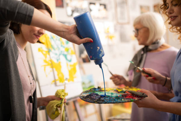 istock Dark-haired art student pouring blue gouache on color palette 1153173411