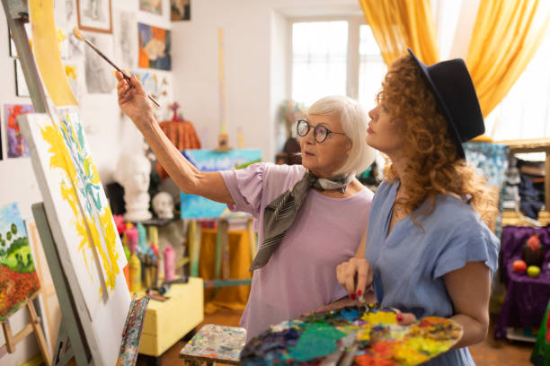 istock Aged grey-haired art teacher in glasses talking to her student 1153173756