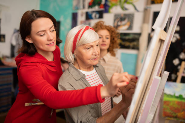 istock Aged art teacher and her students helping her drawing on canvas 1153173838