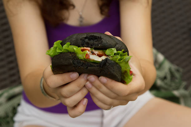 istock hands holding a black hamburger on picnic in summer 1153174415