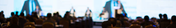 Speech given by speaker on stage at corporate conference. Presenter giving presentation  to audience at leadership workshop for entrepreneurs. Audience receiving business education. Blurred meeting. stock photo