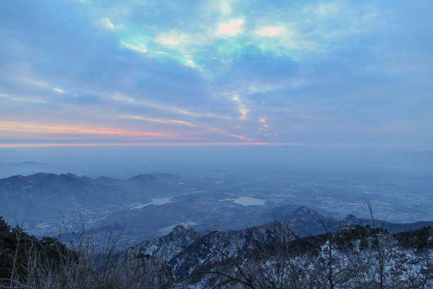 This is the scene taken at the top of mount tai.Mount tai is located in Tai’an City, China.Mount tai is one of the most famous mountains in China.There are many ancient myths and customs about mount tai in China.In ancient China, many emperors had to go to mount tai to offer sacrifices to heaven and earth.Mount tai has a very important historical and cultural status in China.Mount tai sunrise many people want to see the scene, but it is very difficult .Mount tai is also a UNESCO world cultural and natural heritage site. el monte tai encabeza la montaña. tai ' an, china-invierno 2017: vista desde la cima del monte tai, la cima del monte tai. rocas y nieve en los picos. pinos en la cima. las montañas en la distancia se han ido. las nubes lo causaron. las nubes en el cielo
