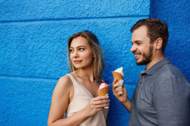 istock Young couple with ice cream on blue wall bckground 1153188337