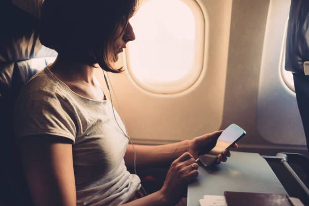 istock Young woman on a plane with a smartphone in her hands 1153198726