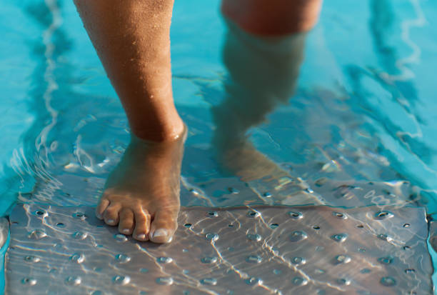 adult white caucasian europian woman's legs with orange ultraviolet pedicure underwater in swimming pool.  Summer. Funny underwater legs in swimming pool, vacation and sport concept.