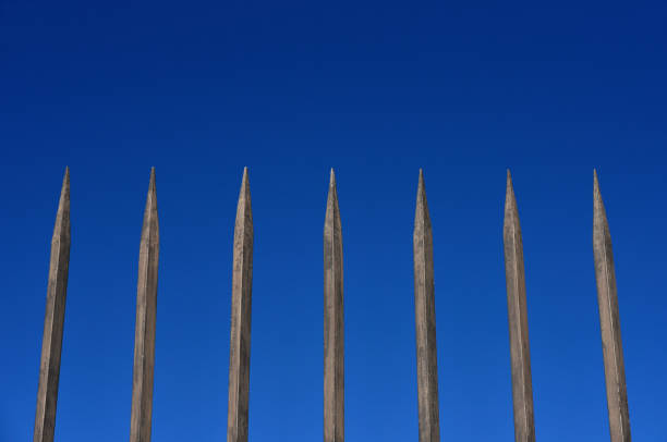 barrera de acero con barras puntiagudas contra el cielo azul - reclusion fotografías e imágenes de stock