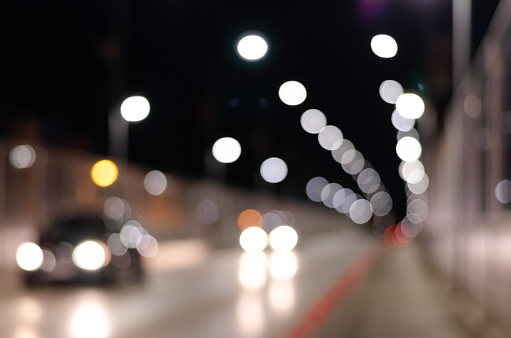 Out of focus   background of city road with multicolored  brightly glowing street lights and moving cars.