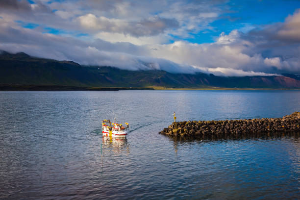 White fishing boat in the harbor pier fishing village Arnastapi. Sunset on the sea fjord in Iceland