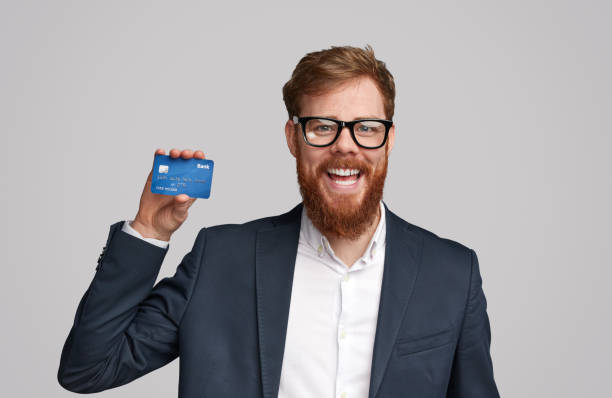 istock Cheerful ginger man presenting banking card 1153206649