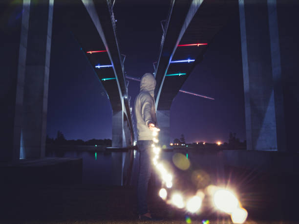 Man with glowing garland under bridge