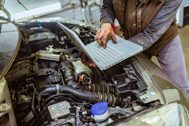 istock Mechanic standing next to the Car And Using Laptop 1153208065