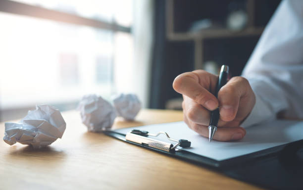 businessman writing on the table with paper balls - paper crumpled letter ideas imagens e fotografias de stock