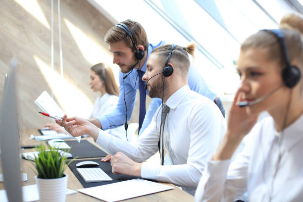 istock Phone operator working at call centre office helping hiss colleague. 1153209628