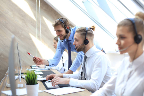 istock Phone operator working at call centre office helping hiss colleague. 1153209642