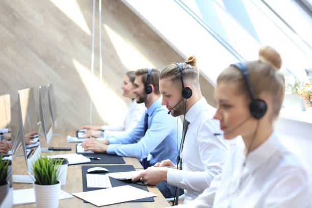 Portrait of call center worker accompanied by his team. Smiling customer support operator at work.