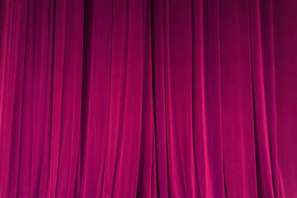 istock closed red curtain background spotlight beam illuminated. Theatrical drapes. 1153210747