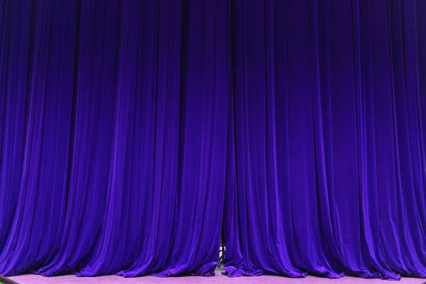 istock closed blue curtain background spotlight beam illuminated. Theatrical drapes. 1153210749