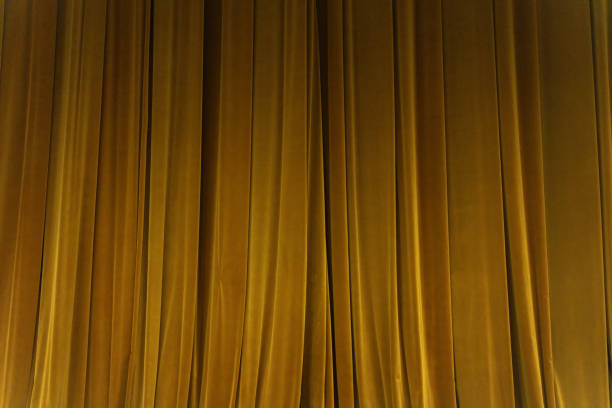 istock closed yellow curtain background spotlight beam illuminated. Theatrical drapes. 1153210751