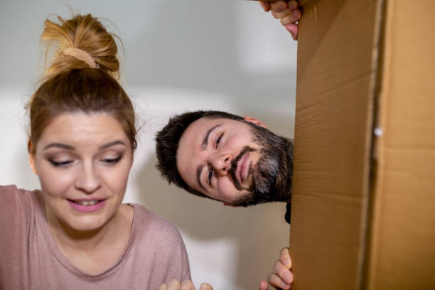 istock Beautiful couple looking at camera and smiling while packing boxes for move 1153210913