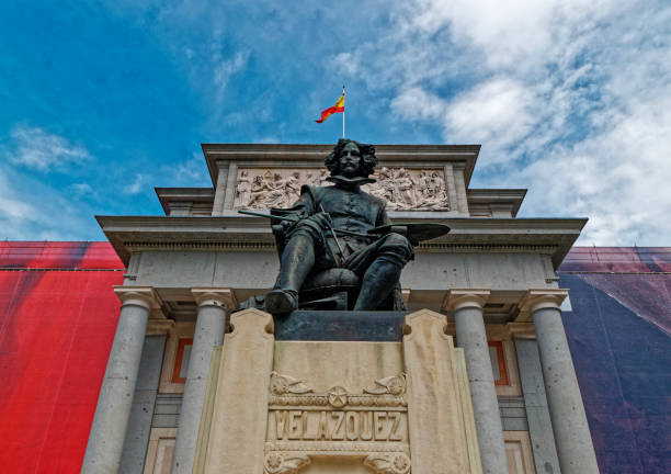Painter Diego Velazquez monument - Prado Museum - Madrid, Spain The statue of the painter Diego Velazquez in front of the Prado Museum in Madrid, was sculpted in 1899 by Aniceto Marinas. It is located at the main entrance of the museum and outside it. Specifically we can see it on the street with the name of Paseo del Prado. The statue represents the painter, Velazquez, posing seated with his brushes and his palette. museo del prado stock pictures, royalty-free photos & images