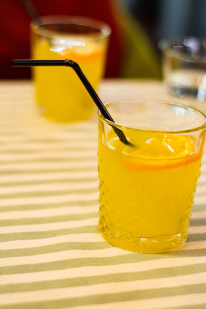 istock Two glasses with orange lemonade on the table in a cafe. 1153213268