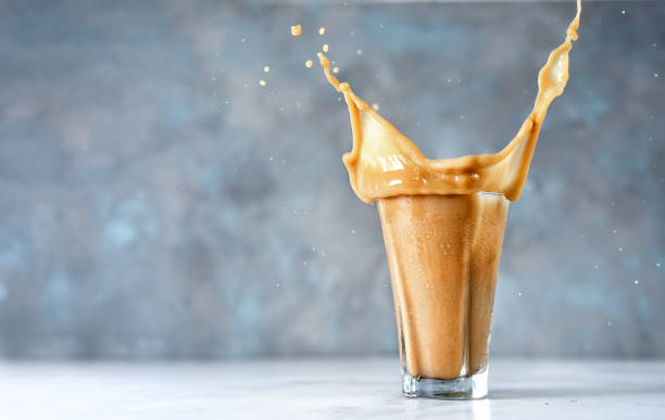 istock Big splash into glass of cappuccino on blue background 1153218352