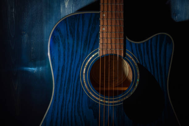 erdachte akustikgitarre auf blauem holzhintergrund im dunkeln. - guitar classical music classical style jazz stock-fotos und bilder
