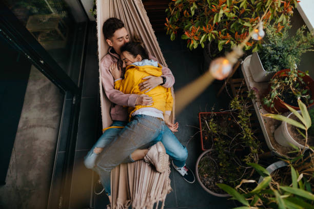 Relaxing moments in a hammock Photo of a young couple having a relaxing moment in a hammock on a terrace of their apartment swinging couples stock pictures, royalty-free photos & images