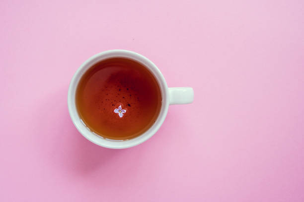 istock Cup of tea with lilac flower on a pink background 1153224817