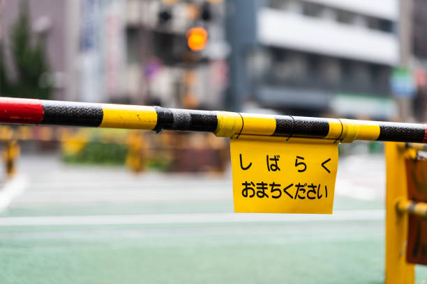 東京・渋谷通りの歩道道、踏み切りでの昼間の建物による道路、クローズドゲートサイン翻訳しばらくお待ちください - crossing railroad track boundary gate ストックフォトと画像