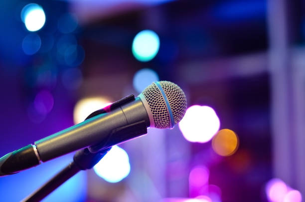 primo piano del microfono su uno sfondo sfocato con luci multicolori durante un concerto. - asta del microfono foto e immagini stock