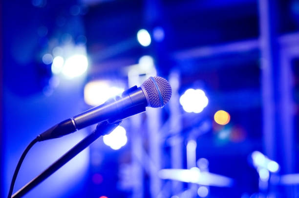 istock Close-up  of microphone on  empty  stage  with multi colored   blurred  background  lights     at a concert . 1153230038