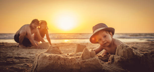 glücklicher kleiner junge und sein vater bauen sandburg am strand - lifestyles child beach digging stock-fotos und bilder