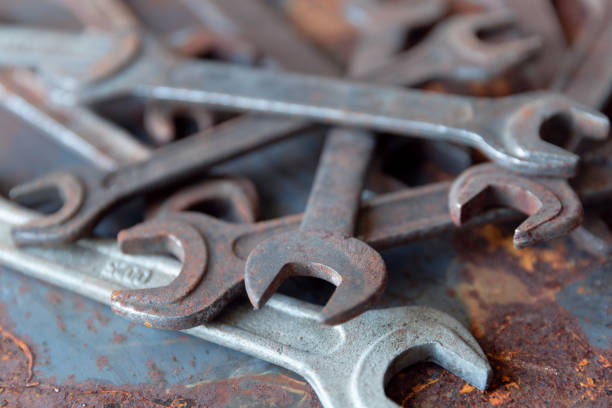 istock Old rusty wrench over battered metal table rough style. Wrenches top view for construction, industrial, electrician concept design 1153230250