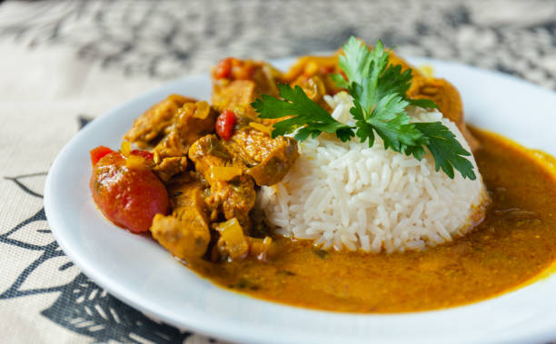 Curry chicken bright juicy with white rice on plate over the tablecloth background. side view. Curry chicken bright juicy with white rice on plate over the tablecloth background. side view. Stock photo chicken curry stock pictures, royalty-free photos & images