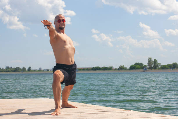 istock Young man doing yoga and meditating in warrior pose on beach 1153233653
