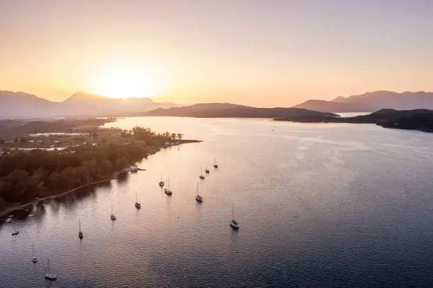 Photo of yachts are on the water near the island. Golden sunset sun. Aerial photo