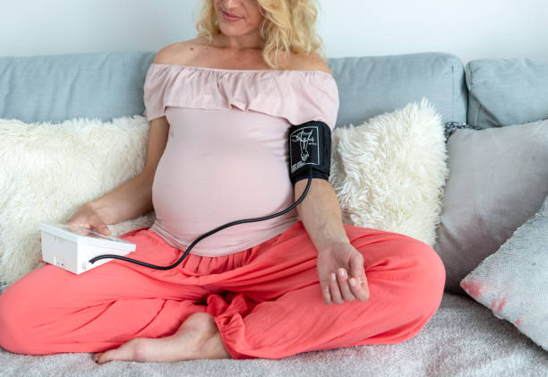 беременная женщина, смотрявшая свое кровяное давление дома - blood pressure gauge surveillance home interior house стоковые фото и изображения