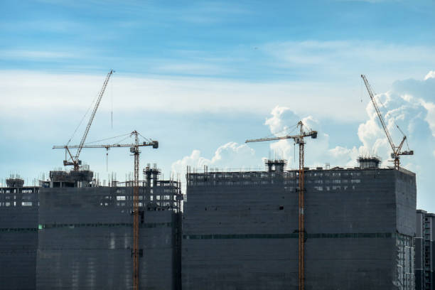 istock Building crane and buildings under construction and cloudy sky 1153238783