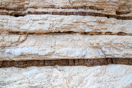 White and brown limestone mountain, layered rock, natural stone near Mediterranean Sea in Gargano, Italy. Background, close-up