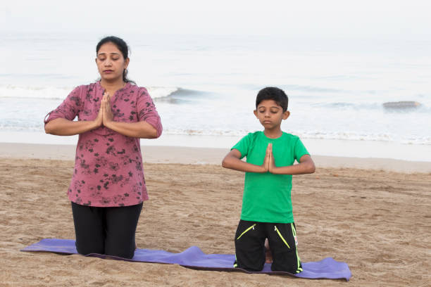 istock Mother and son doing yoga at beach 1153243680