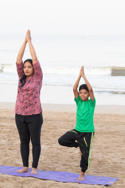 istock Mother and son doing yoga at beach 1153245103