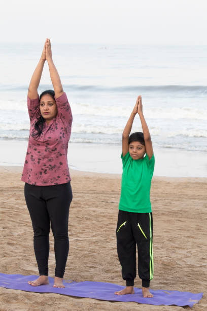 istock Mother and son doing yoga at beach 1153245405
