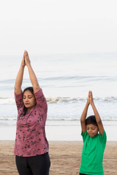 istock Mother and son doing yoga at beach 1153246066