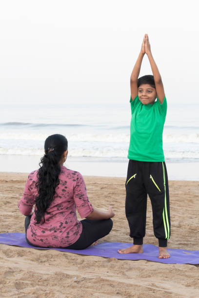istock Mother and son doing yoga on the beach 1153246132