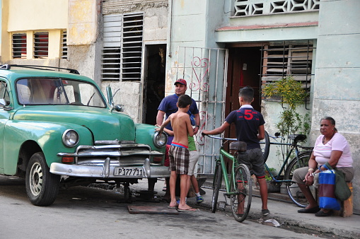 So much of Cuban life takes place on the city streets: negotiating with ambulant vendors, gossiping and board games with neighbors, picking up a wifi signal in one of the rare spots with a strong signal, preparing food for dinner, etc. In this shot, neighbors gather around a parked classico. Photos taken in Havana, Cuba on 1/9/2016.
